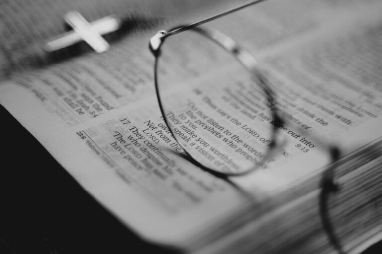 Close-up of eyeglasses resting on an open Bible, symbolizing study and reflection, shared by Bible Digest.